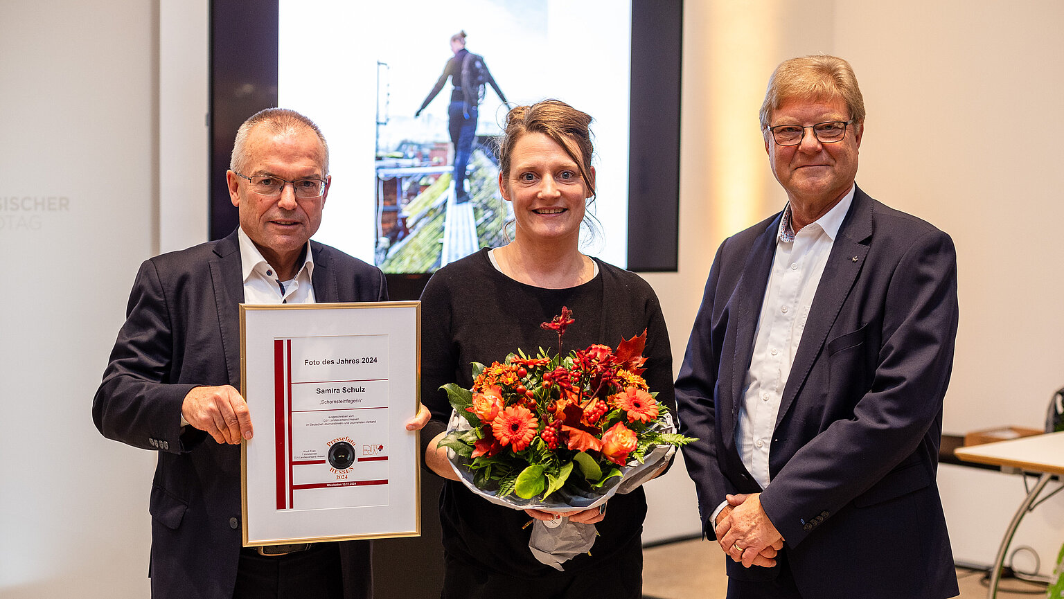 Matthias Haupt (Sparkassen-Giroverband Hessen/Thüringen) mit Preisträgerin Samira Schulz ("Foto des Jahres 2024" Schornsteinfegerin) und Knud Zilian (Erster Vorsitzender DJV Hessen) im Hessischen Landtag bei der Preisverleihung "Pressefoto Hessen 2024" – Matthias Haupt (Sparkassen-Giroverband Hessen/Thüringen) mit Preisträgerin Samira Schulz ("Foto des Jahres 2024" Schornsteinfegerin) und Knud Zilian (Erster Vorsitzender DJV Hessen) im Hessischen Landtag bei der Preisverleihung "Pressefoto Hessen 2024"